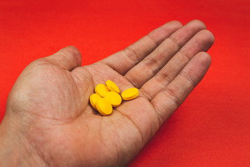 hand holding yellow pharmaceutical medicine pills