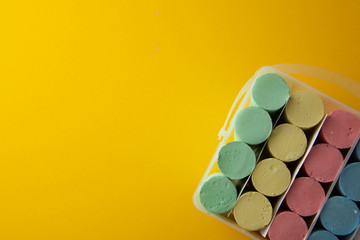 Colorful chalks over yellow background with copy space. Education template. Childhod, business and design.