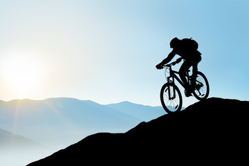 Fototapeta na wymiar Silhouette of Cyclist Riding the Bike Down the Rock at Sunrise. Extreme Sport and Enduro Biking Concept.