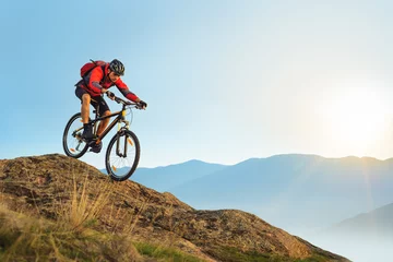 Fotobehang Cyclist in Red Riding the Bike Down the Rock at Sunrise. Extreme Sport and Enduro Biking Concept. © Maksym Protsenko