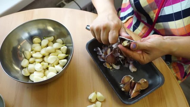 Cleaning garlic with a knife.