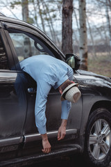 Dead businessman in his car hanging in the window. The concept of the crime of murder