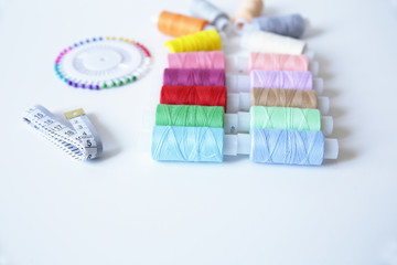 spools of colorful thread, meter and needles on white background. With copy space for text.