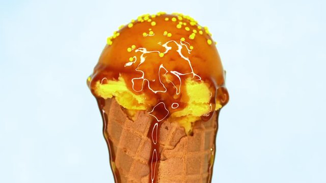 Lemon sprinkled ice-cream in waffle cone rotating on white background and liquid caramel topping pouring on it. Delicious isolated sweet dessert in studio