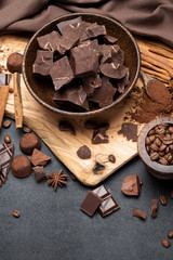 Dark or milk organic chocolate pieces and truffle candies in wooden bowl on dark concrete backgound