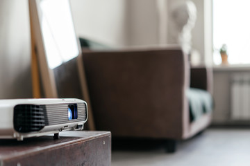 A digital projector stands on a pedestal in the interior of a teaching class with a sofa and a...