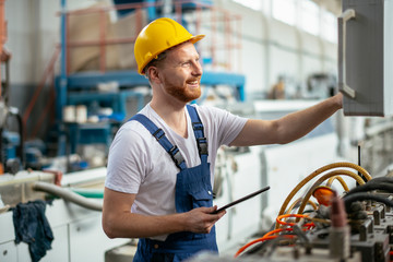 Factory worker. Man with helmet working on wires.