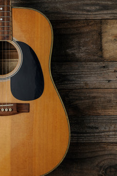 An acoustic guitar on grunge wood background to use as book cover for a guitar course
