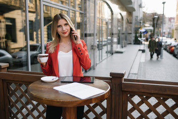Businesswoman taking a coffee break and using smartphone.