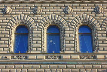 Fototapeta na wymiar Building facade with ornamental exterior design and three arch windows in row
