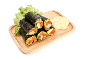 Fresh vegetable spring roll. Salad roll in Seaweed tube on wooden plate. Clean food. Salad for weight loss on white background
