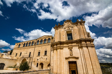 Fototapeta na wymiar Warm scenery summer day street view in front of Chiesa di Sant'Agostino in the ancient town of the Sassi. Sun lights the beautiful medieval church. Matera, Basilicata region, Italy
