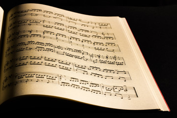 Fototapeta na wymiar Close-up of sheet music page, in black background