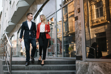 A two young business-people are walking along office building