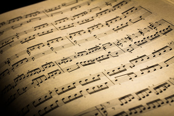 Close-up of sheet music page, in black background