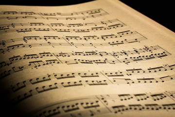 Close-up of sheet music page, in black background