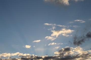 Fototapeta na wymiar raios solares entre nuvens no céu azul