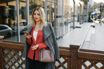 Young fashionable business woman in hurry on city street, talking on mobile phone