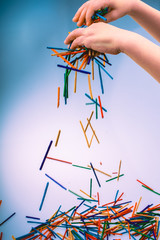 Hand letting coloured wooden  sticks drop on white