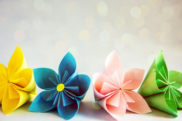  Beautiful paper flowers of different colors. Multi-colored origami flowers on a blue background,...