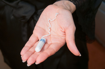 The girl is holding a close-up tampon for menstruation. The concept of women's health