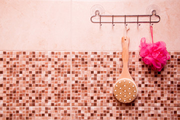 some accessories for a bath hanging on hooks on a background of marble tiles and mosaics. Sponge...