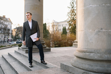 Two confident business colleagues walking on office terrace. Mid adult business man and woman discussing document outdoors on coffee break. Working during break concept