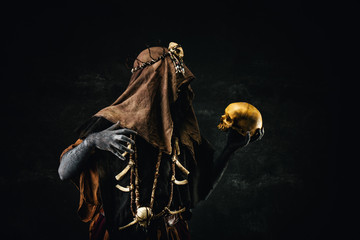 Portrait of a shaman holding a human skull in his hands