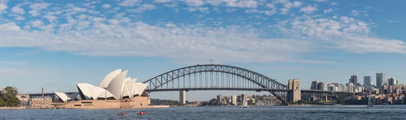 Poster Kajakkers peddelen in de haven van Sydney, met de beroemde Harbour Bridge en het Opera House op de achtergrond © Michael Evans