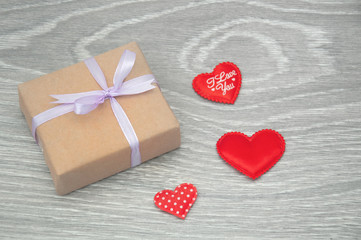 Fototapeta premium Gift box with red hearts on gray wooden background. Greeting card for Valentine's Day.