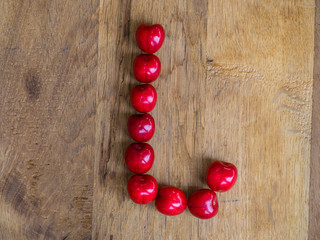 cherry on wooden background as a letter