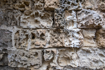 Ancient pastel warm colors stone wall with bricks eaten by the rain and time, background or wallpaper usage, Matera, Basilicata region in Italy