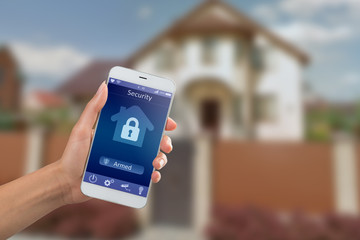 Smartphone with home security app in a hand on the building background