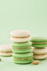 Stack of pistachio macarons on green background.