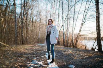 Fototapeta premium A girl walks along a forest trail through the last snow.