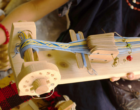 Weaving loom with fibers and inkle blu and yellow - Powered by Adobe