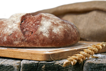 Round bread and wheat ears and a burlap cloth on the old wooden table