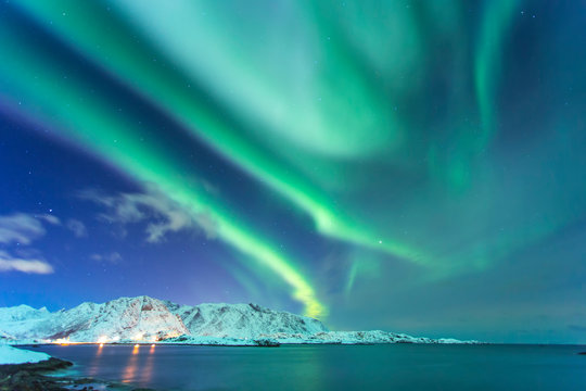 Northern lights at night against the backdrop of beautiful mountains by the ocean in the Lofoten Islands