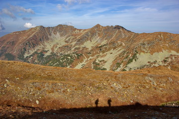 autumn mountain coloured to orange and silhouettes of people