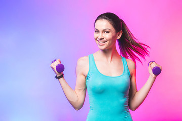 Portrait of young attractive happy woman in sport clothes with beautiful smile holding weight...