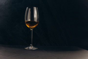 a glass of white wine on a black background. the smoke from the hookah envelops the glass. rest, holiday. alcoholic drink closeup. white fog