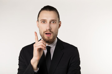 Surprised beautiful bearded guy with good-looking hairstyle, wearing black suit and tie