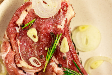 Marinated beef rib eye steak on bone with spices, onion and rosemary on wooden table