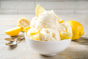 Homemade lemon vanilla ice cream with fresh lemon slices. Sweet and sour summer dessert. Wooden background copy space - obrazy, fototapety, plakaty
