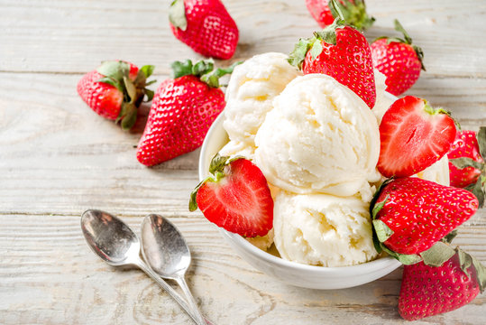 Homemade strawberry vanilla ice cream with fresh strawberries. Sweet berry summer dessert. Wooden background copy space