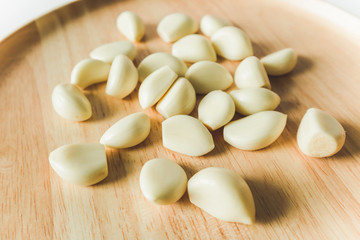 Fototapeta na wymiar Peeled Garlic cloves close up on round wooden plate