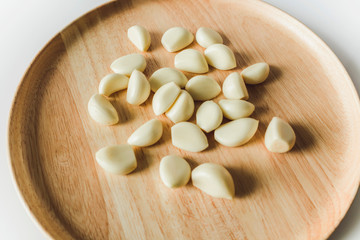 Peeled Garlic cloves on round wooden plate