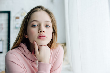 Teenage child in casual pink hoodie looking at camera