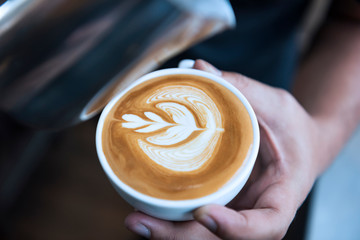 Barista making latte or Cappuccino art with frothy foam, coffee cup in cafe.