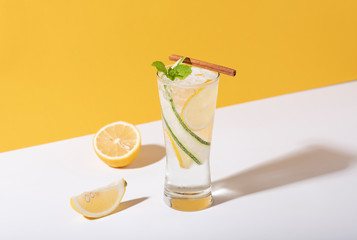 Mojito cocktail with lemon and mint in glass on yellow background. summer drink.